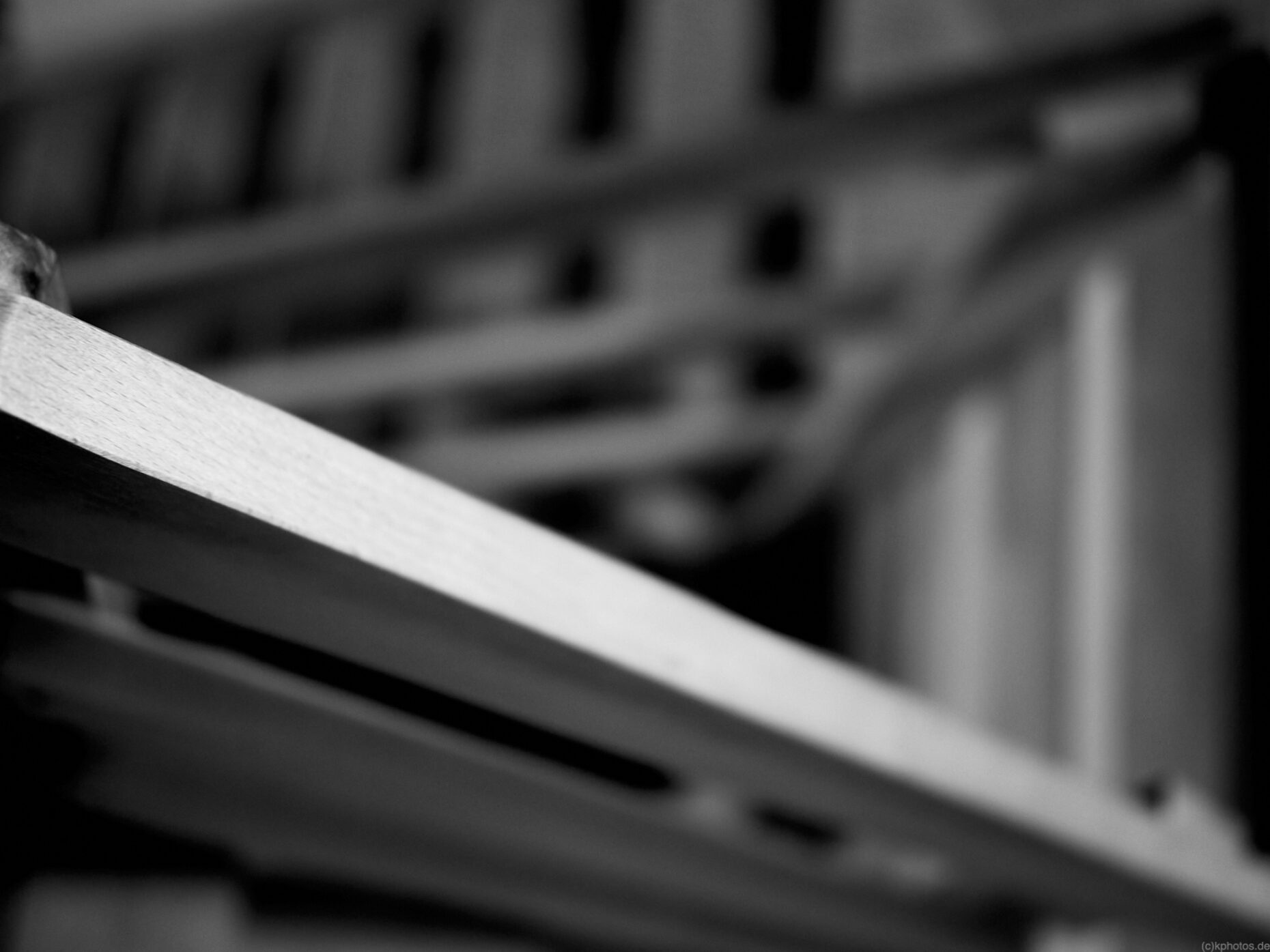 an abstract black and white picture of a wooden staircase, you only see the first railing in focus, and you see the depth as a dark black hole