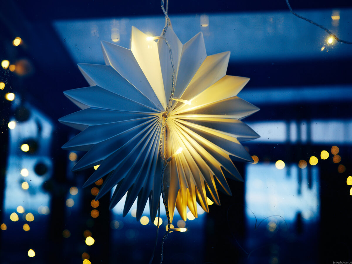 A window with a string of lights at blue hour with lots of bokehs in the background