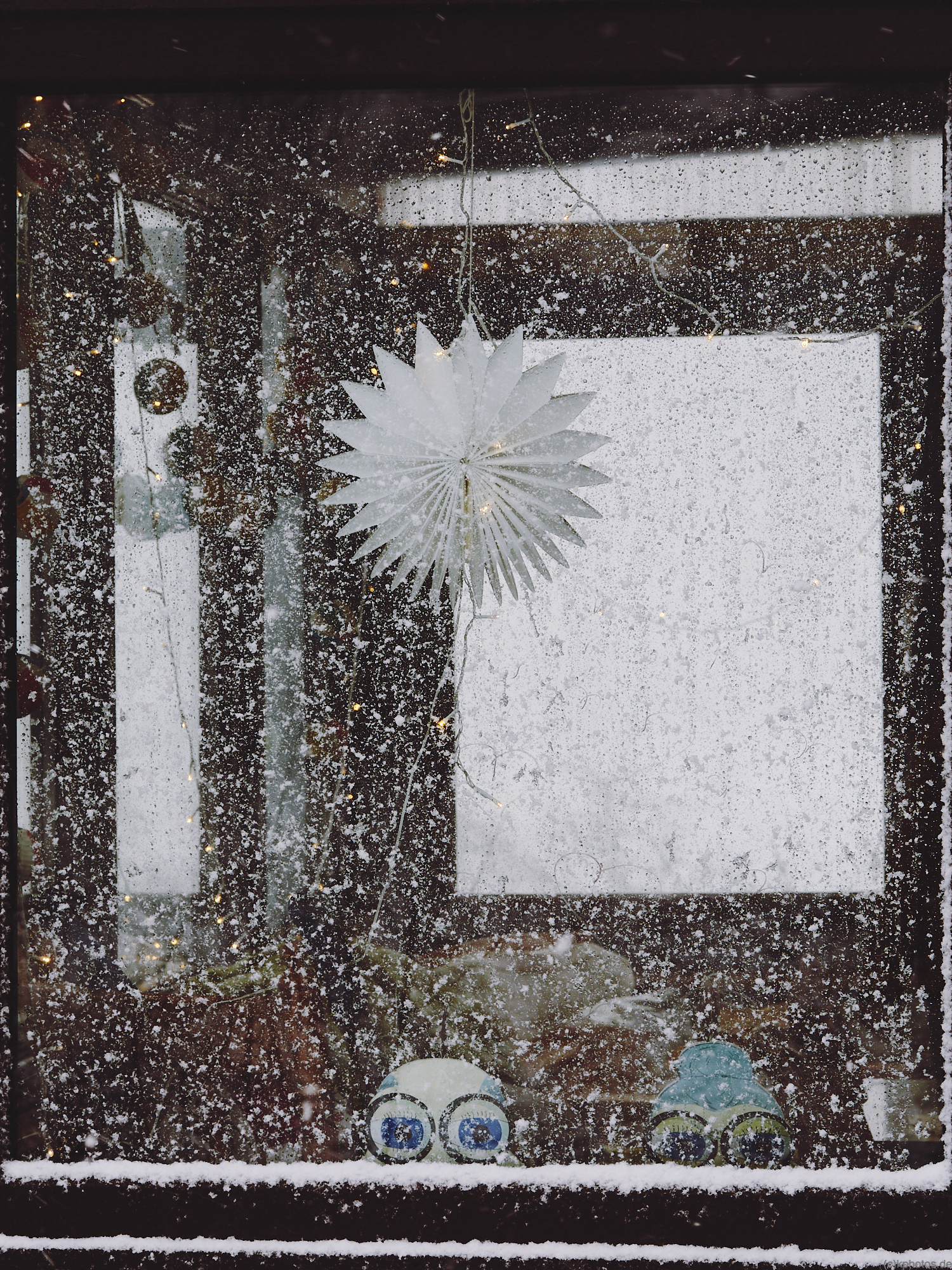 a frozen window with some snowflakes and a starlight in the back.